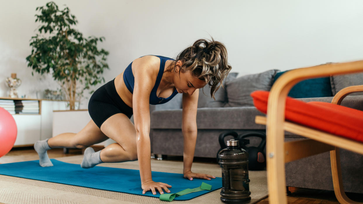  Woman performing mountain climber exercise at home. 