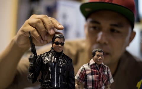 Model toy maker Dennis Mendoza shows miniature dolls of President Rodrigo Duterte as "The Terminator" - Credit: NOEL CELIS/AFP/Getty Images