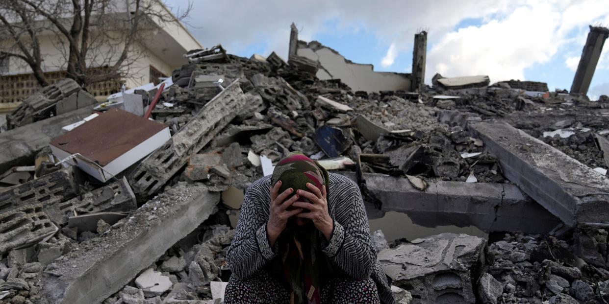 A woman sits on the rubble as emergency rescue teams search for people under the remains of destroyed buildings in Nurdagi town on the outskirts of Osmaniye city southern Turkey, Tuesday, Feb. 7, 2023.