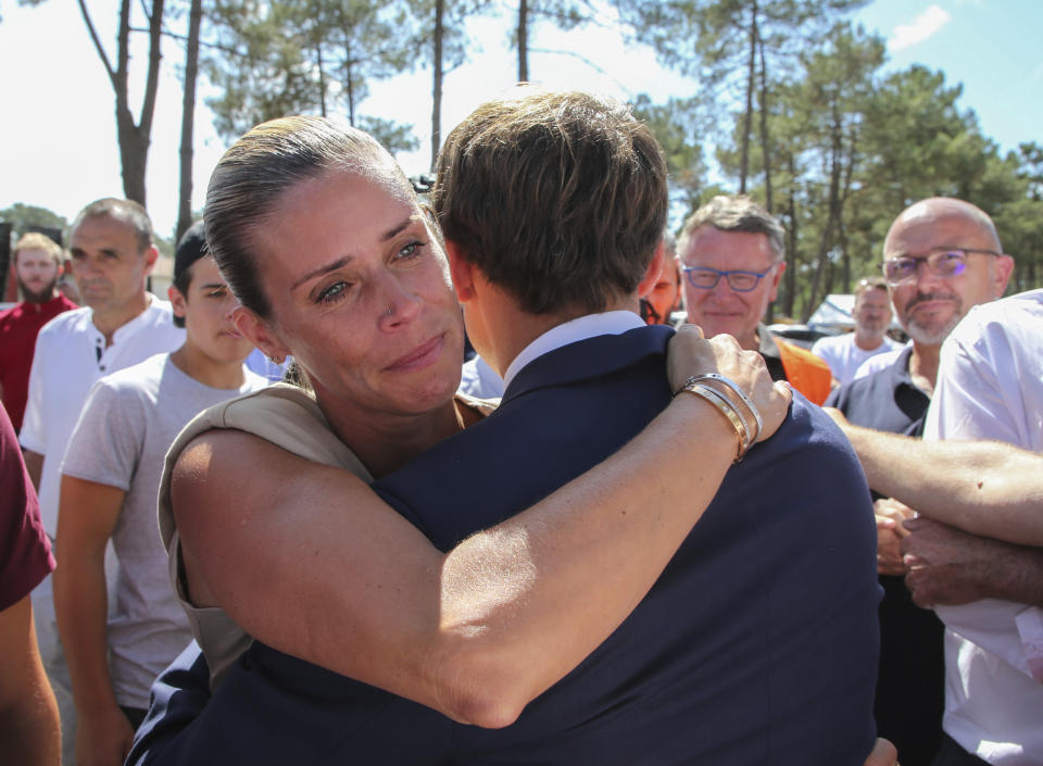 Sandrune Carella, left, owner of the campsite Pyla who burned down in the forest fire hugs French President Emmanuel Macron as he visits La Test-de-Buch, near Arcachon, southwestern France, Wednesday, July 20, 2022. In the Gironde region of southwest France, two massive fires feeding on tinder-dry pine forests also have forced tens of thousands of people to flee homes and summer vacation spots since they broke out July 12. (AP Photo/Bob Edme, Pool)