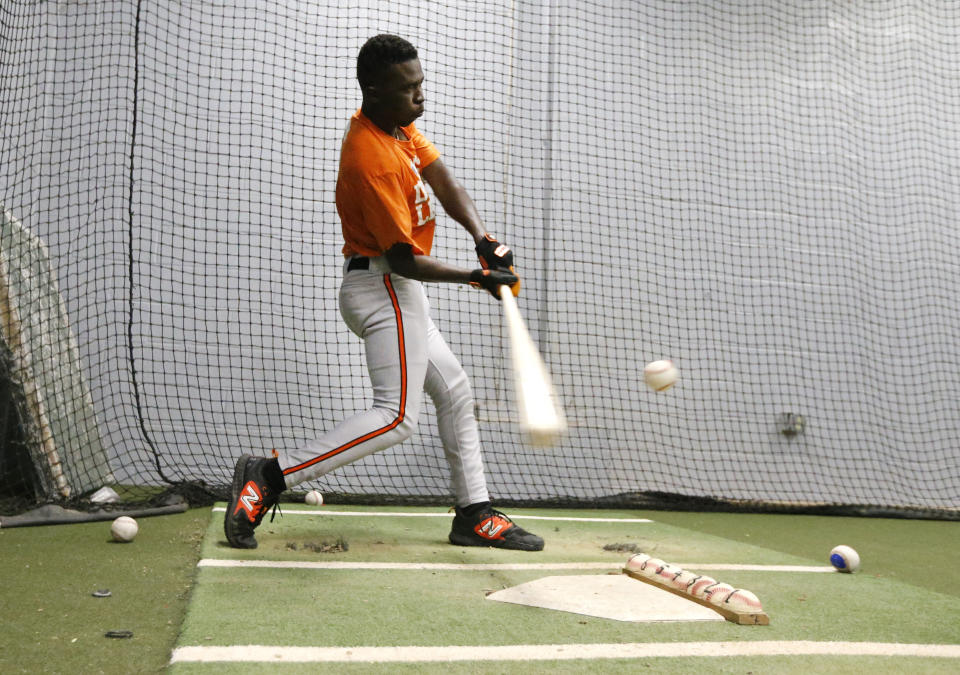 Frederick Keys catcher Dennis Kasumba warms up in a batting cage before the team's baseball game against the Trenton Thunder, Tuesday, July 4, 2023, in Trenton, N.J. Kasumba, from Uganda, dreams of reaching the major leagues someday. The 19-year-old catcher had a chance to play for the Frederick Keys of the MLB Draft League this past month. (AP Photo/Noah K. Murray)