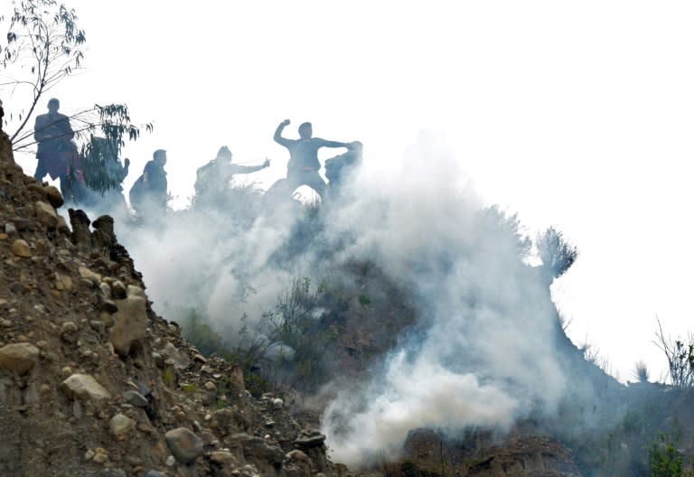 Bolivian coca growers from Los Yungas region confront riot police agents within a tear gas cloud, during a protest against a bill that caps legal coca crops extensions in La Paz on February 21, 2017