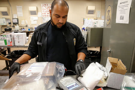 U.S. Customs and Border Protection officer Mohammed Rahman uses a laser to scan packages for contraband in a detention room at the JFK mail facility in New York, U.S., August 28, 2018. REUTERS/Jill Kitchener