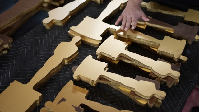 Oscars statue cutouts rest on a table.