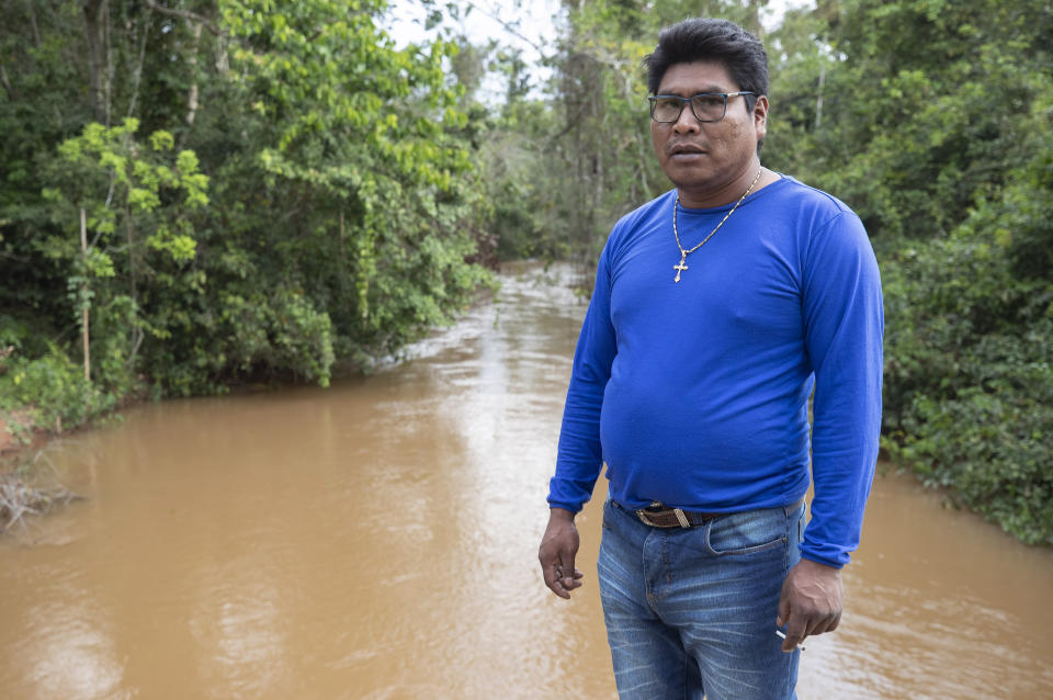 In this Aug. 26, 2019 photo, indigenous leader Saulo Katitaurlu stands next to the Sarare River, in the southwestern Amazon near Conquista D'Oeste, in the Brazilian state Mato Grosso. “Many years ago, the water wasn’t like this,” he told AP journalists, saying increased cattle ranching and soy farming have made muddied the once clear waters. (AP Photo/Andre Penner)