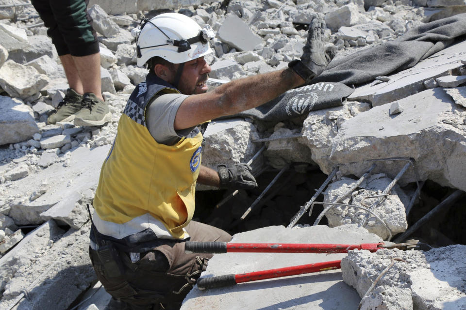 This photo provided by the Syrian Civil Defense White Helmets, which has been authenticated based on its contents and other AP reporting, shows a Civil Defense worker searching for victims from under the rubble of a destroyed building that hit by airstrikes, in Deir al-Sharqi village, in Idlib province, Syria, Saturday, Aug 17, 2019. Syrian activists and a war monitor say airstrikes have pounded the southern edge of a rebel stronghold in the country's northwest, in one instance killing seven including children. (Syrian Civil Defense White Helmets via AP)