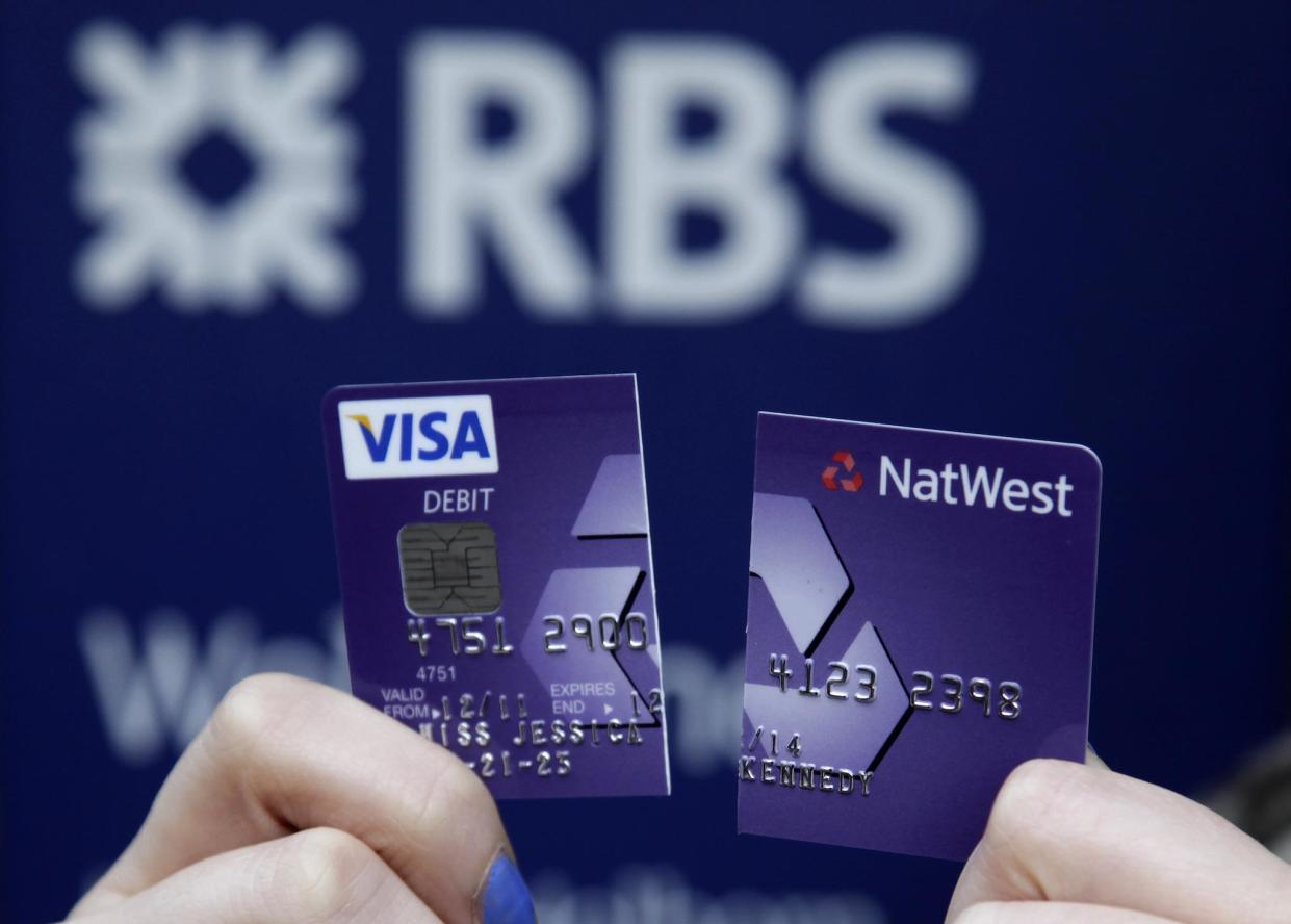 A demonstrator holds up her destroyed NatWest debit card as she stands in front of a branch of the Royal Bank of Scotland (RBS) in London February 23, 2012: REUTERS/Stefan Wermuth