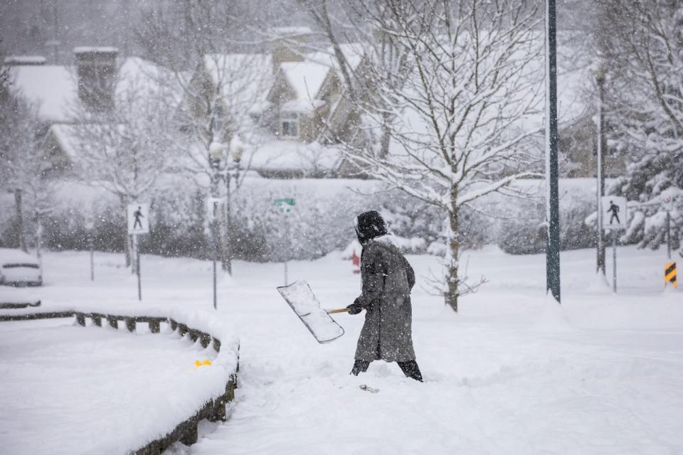 A woman shovels snow during a period of heavy snowfall in Surrey, British Columbia on Wednesday, January 17, 2024. 