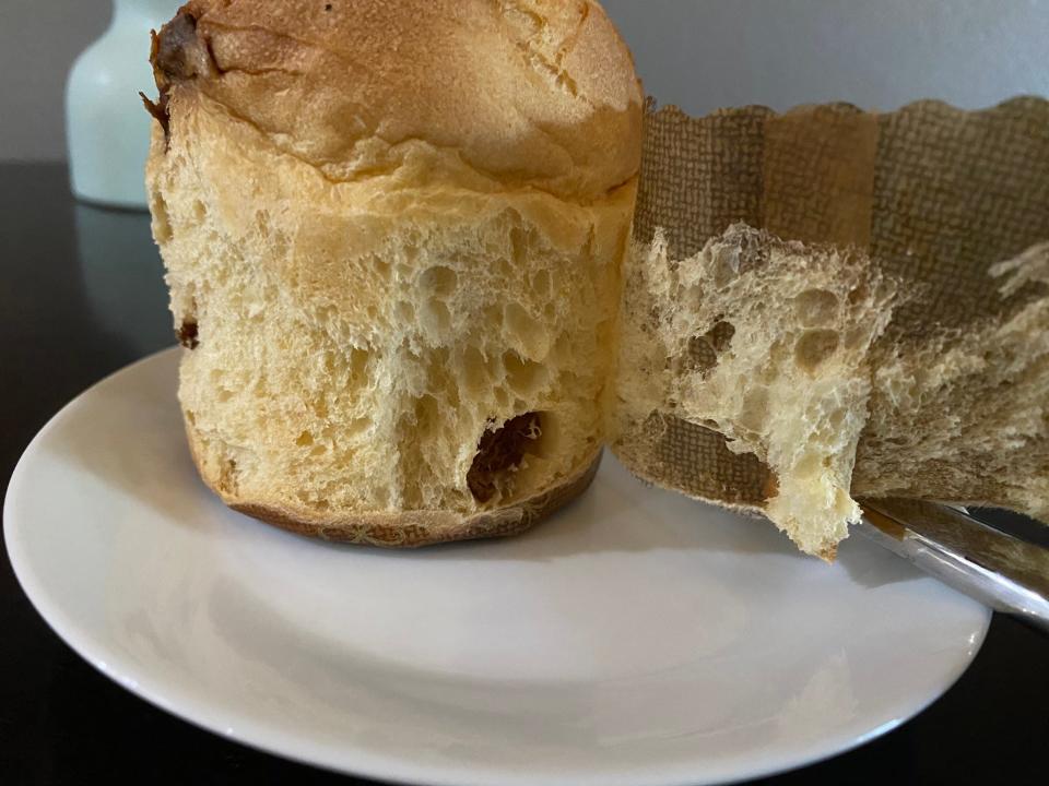 Panettone bread with wrapper being peeled away and some bread sticking to wrapper