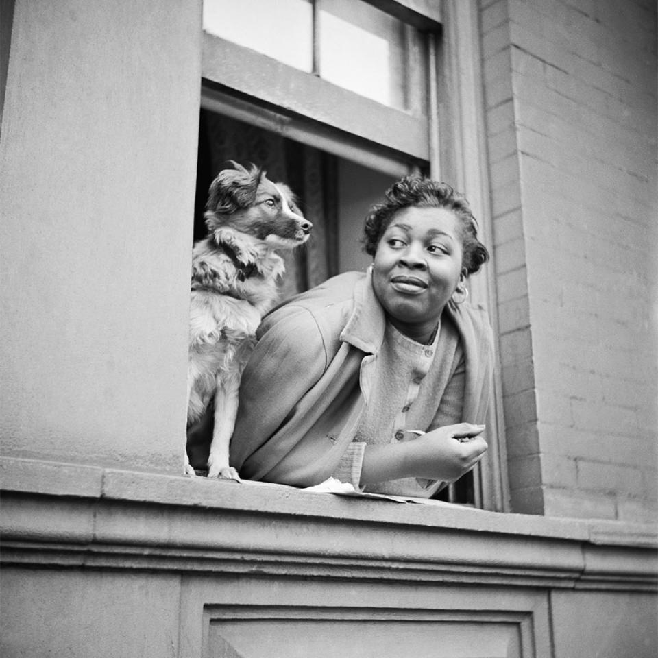 <p>Parks captured a woman and her dog taking in the sights as they looked out from their Harlem apartment in May 1943. </p>