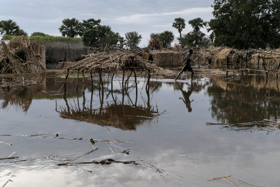 A young man runs between abandoned shelters in Majak Awar village, Northern Bahr el Ghazal State, South Sudan, Wednesday, Oct. 20, 2021, where some 100 families have been displaced twice, in June when homes were flooded and again in August when their shelters were ruined, too. The United Nations says the flooding has affected almost a half-million people across South Sudan since May. (AP Photo/Adrienne Surprenant)