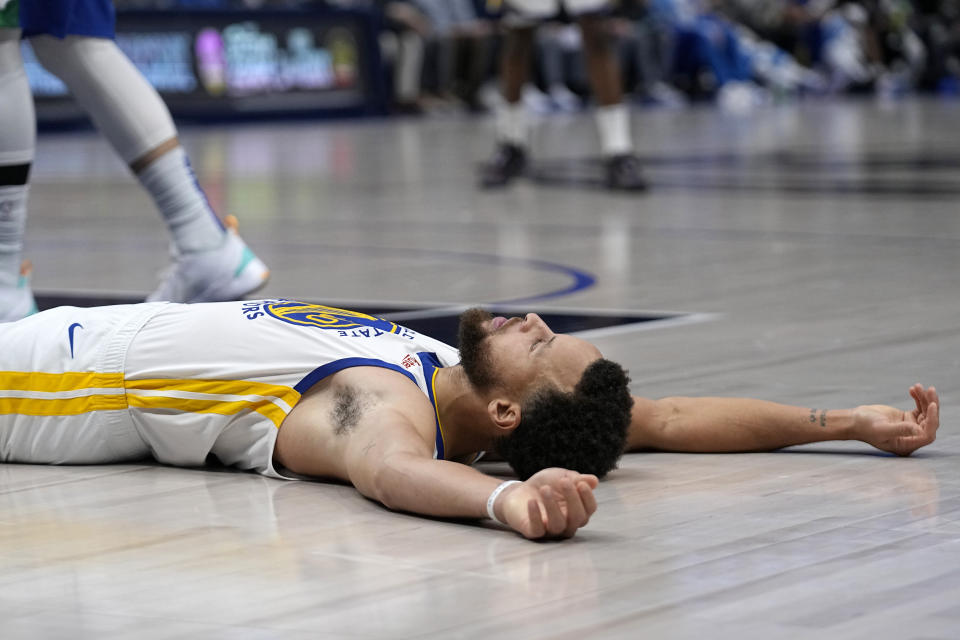 Golden State Warriors guard Stephen Curry lays on the ground after being fouled taking a shot in the second half of an NBA basketball game against the Dallas Mavericks in Dallas, Tuesday, Nov. 29, 2022. (AP Photo/Tony Gutierrez)