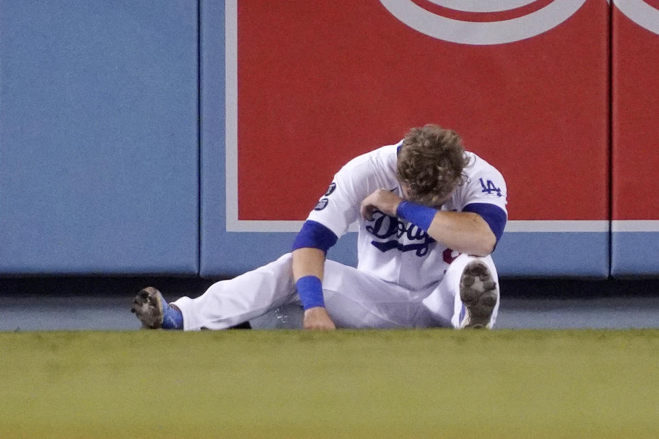 Los Angeles Dodgers second baseman Gavin Lux falls sits on the ground after missing a catch on a ball hit for an RBI triple by San Diego Padres' Wil Myers and running into the wall during the sixth inning of a baseball game Wednesday, Sept. 29, 2021, in Los Angeles. (AP Photo/Mark J. Terrill)