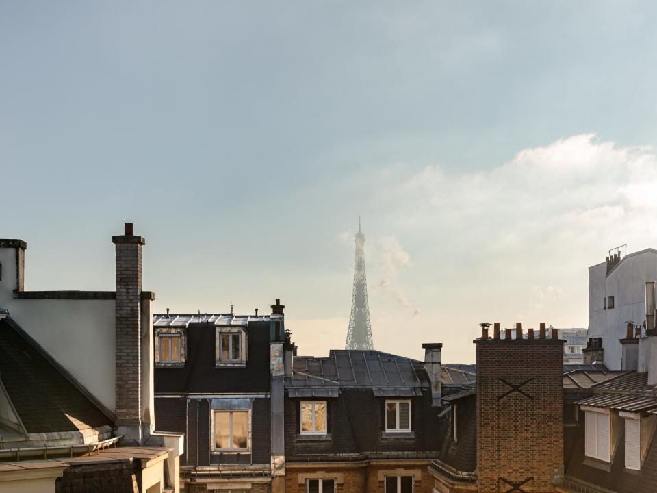 A view of the Eiffel Tower over building rooftops.