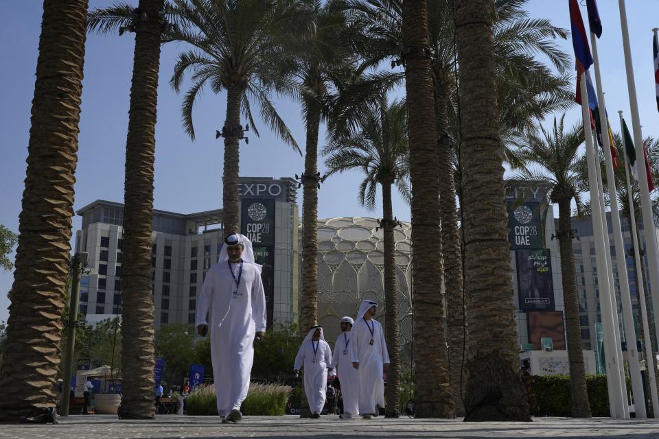 People walk through the COP28 U.N. Climate Summit with Al Wasl Dome in the background at Expo City, Sunday, Dec. 10, 2023, in Dubai, United Arab Emirates. (AP Photo/Rafiq Maqbool)