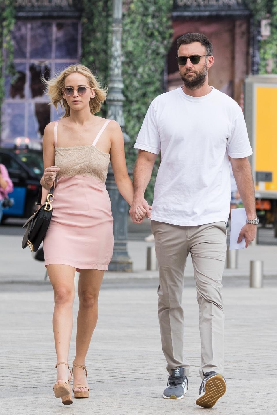 the two hold hands as they walk down the street