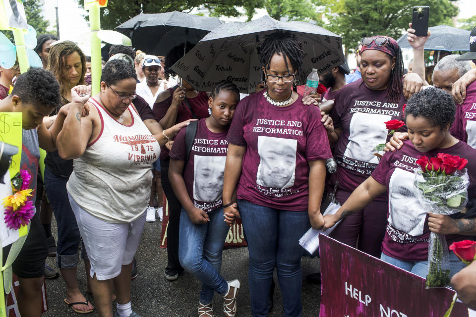 FILE - In this June 2, 2018, file photo, family members, including Princess Blanding, center right, sister of Marcus-David Peters, her daughter, Tionna Blanding, center left, cousin Rachel Melvin, right, and others pray after a march for Peters in front of Richmond Police Headquarters in Richmond, Va. Around the U.S., protesters have been calling for prosecutors to take a second look at police killings of Black people, including Peters. Peters was shot May 14 by a Richmond police officer after a confrontation on Interstate 95. (Daniel Sangjib Min/Richmond Times-Dispatch via AP, File)