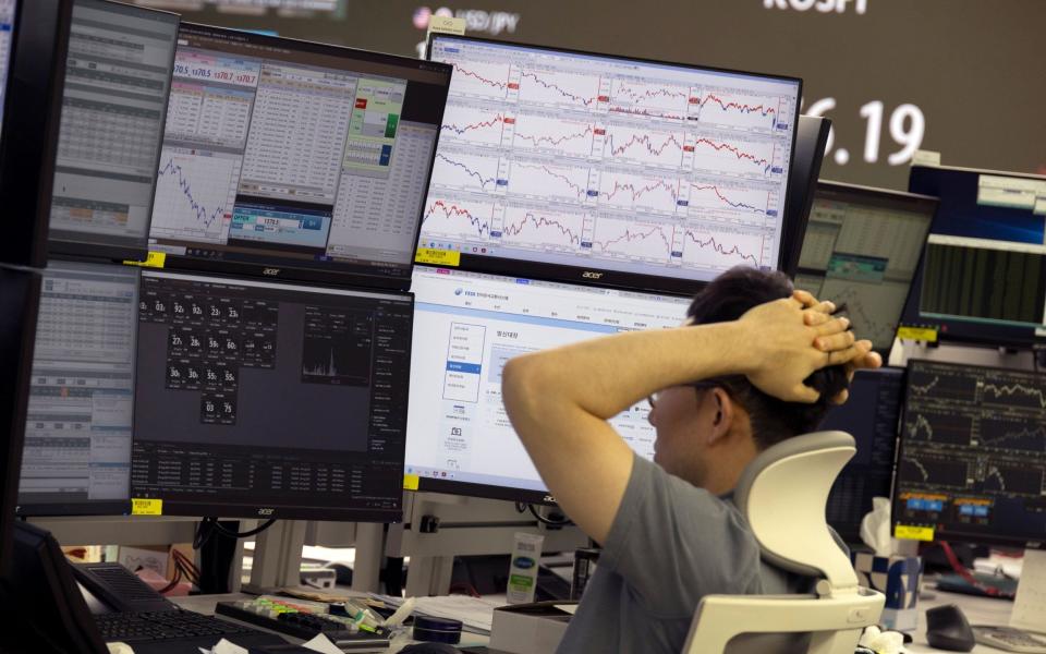 A South Korean dealer works in front of monitors at the Hana Bank in Seoul after Asian stock markets plummeted