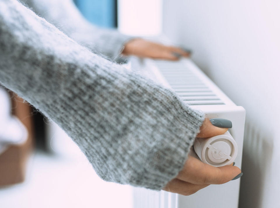 Woman turning the knob on a radiator 