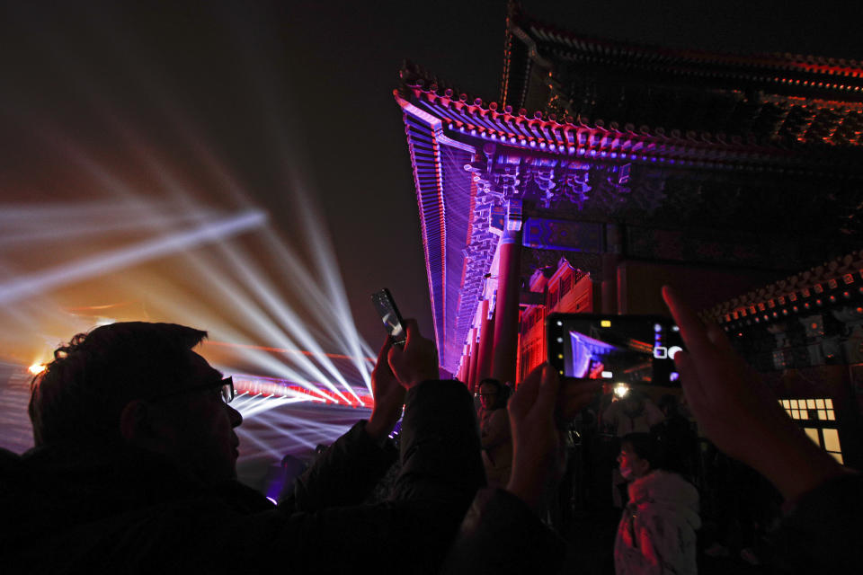 Visitors take souvenir photos of the Forbidden City illuminated with lights during the Lantern Festival in Beijing, Tuesday, Feb. 19, 2019. Beijing's Palace Museum was illuminated and opened for night visits to celebrate China's Lantern Festival. For the first time since it was established 94 years ago, the Palace Museum, also known as the Forbidden City, extended opening hours till nighttime and lit up part of its cultural relics buildings. (AP Photo/Andy Wong)