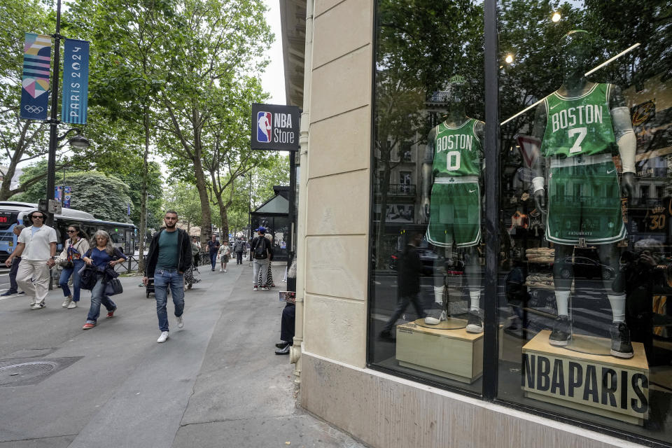 People walk past the NBA store in Paris Thursday, June 20, 2024. New names will soon adorn replica NBA jerseys of French youths competing on basketball courts around Paris. Frenchmen Zaccharie Risacher, Alexandre Sarr and Tidjane Salaün are among the top picks in the NBA draft, where a second straight French No. 1 pick is expected after Victor Wembanyama last year. (AP Photo/Michel Euler)