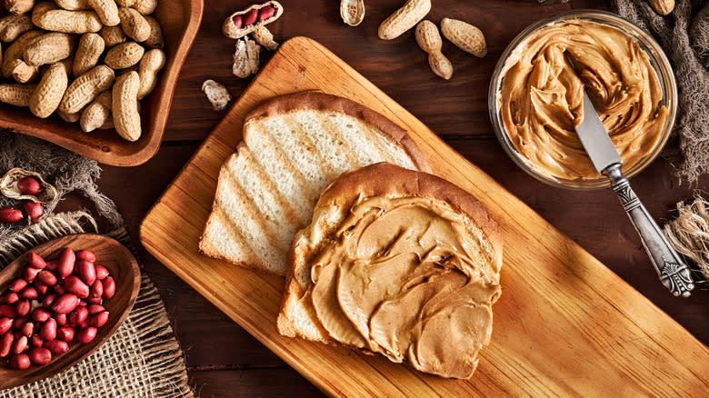 Peanut butter in jar and on toast with peanuts