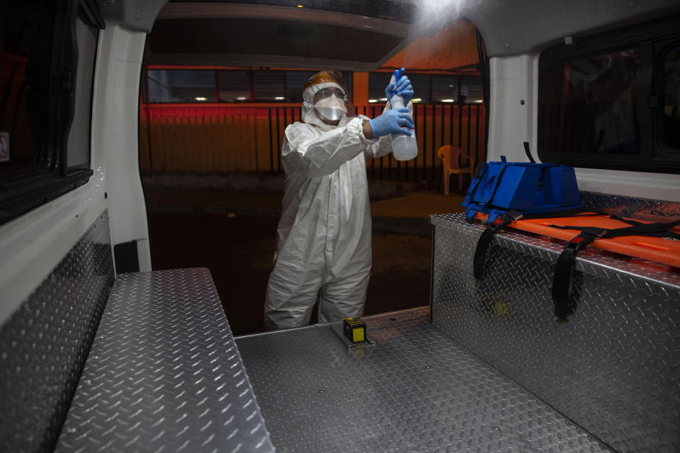 A firefighter wearing gear to protect against the coronavirus disinfects an ambulance outside the COVID-19 unit at San Juan de Dios hospital in Guatemala City, Monday, June 8, 2020. (AP Photo/Moises Castillo)