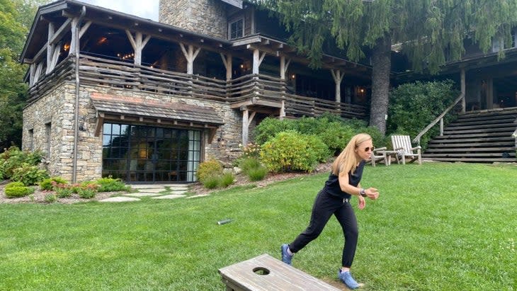 A woman playing cornhole on the lawn