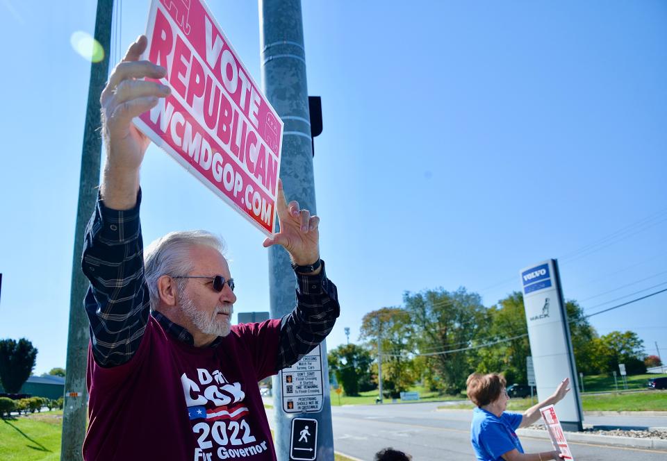 Ray Foltz, left, of Hagerstown, holds a sign outside the entrance to Volvo Group Trucks on Maugans Ave in Hagerstown Friday ahead of President Biden's visit.