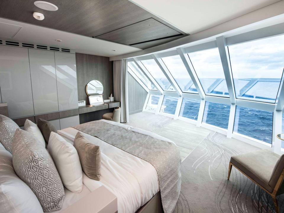 a bed, desk, and chair overlooking the ocean in the Iconic Suite of the Celebrity Edge