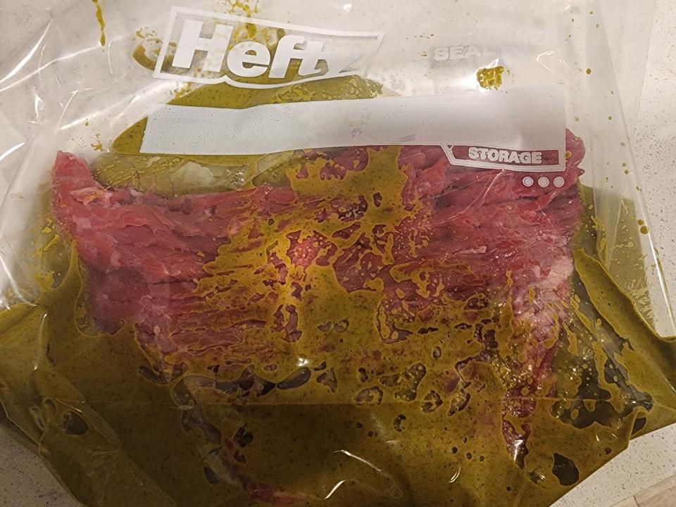Raw steak in a plastic bag with a green marinade
