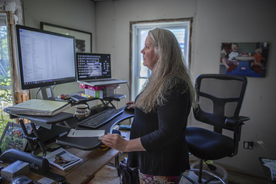 Lisa Edson Neveu, 52, works at the main room of her house in Montpelier, Vt., July 3, 2024 that was damaged by the 2023 flood. A year after catastrophic flooding inundated parts of Vermont, some homeowners are still in the throes of recovery. (AP Photo/ Dmitry Belyakov)