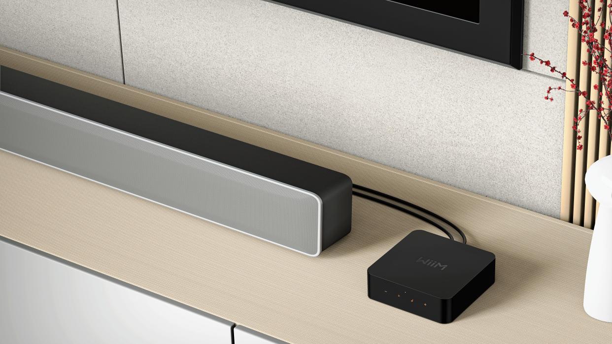  Press image of WiiM Pro with soundbar speaker on a sideboard. 