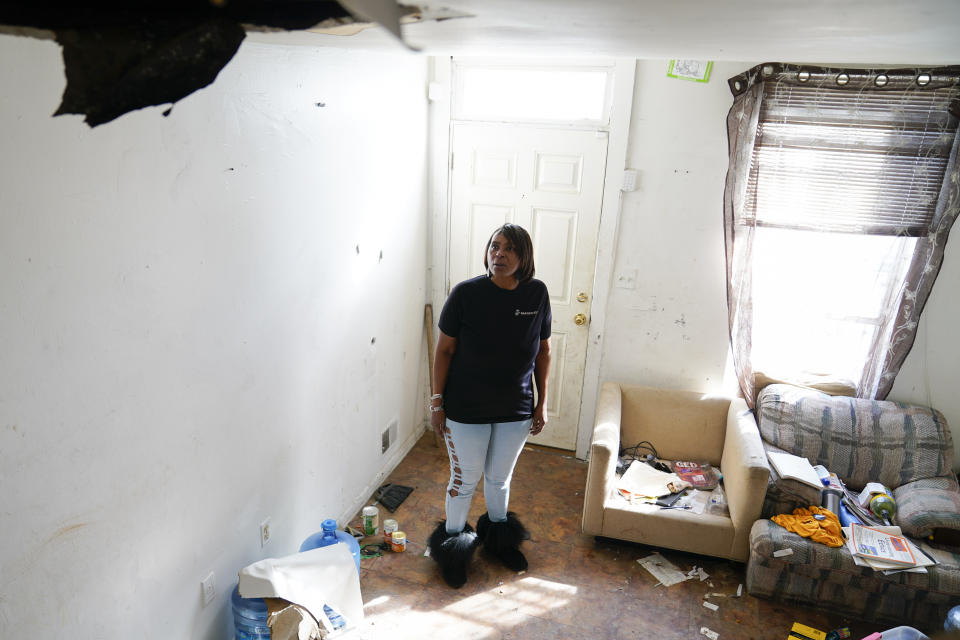 Angela Banks looks through the unkept living room of the house she used to rent, Wednesday, Feb. 15, 2023, in Baltimore. In 2018, Banks was told by her landlord that Baltimore officials were buying her family's home of four decades, planning to demolish the three-story brick rowhouse to make room for an urban renewal project aimed at transforming their historically Black neighborhood. Banks and her children became homeless almost overnight. Banks filed a complaint Monday asking federal officials to investigate whether Baltimore's redevelopment policies are perpetuating racial segregation and violating fair housing laws by disproportionately displacing Black and low-income residents. (AP Photo/Julio Cortez)