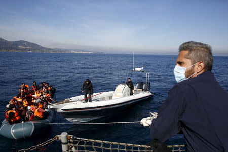 Greek Coast Guard officers tug a dinghy carrying refugees and migrants towards the Ayios Efstratios Coast Guard vessel, during a rescue operation in the open sea between the Turkish coast and the Greek island of Lesbos, February 8, 2016. REUTERS/Giorgos Moutafis