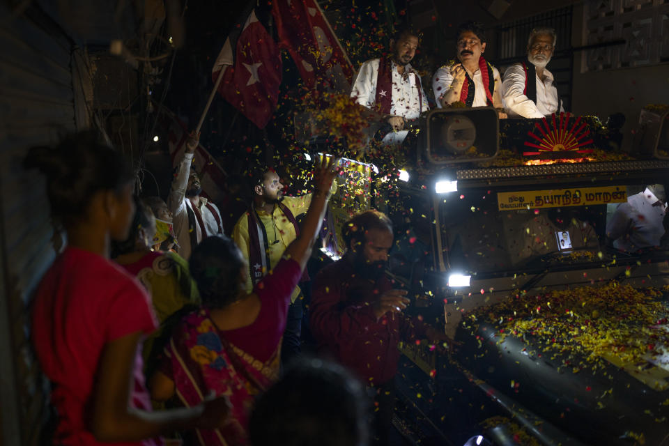 A woman showers flower petals as Dravida Munnetra Kazhagam (DMK) party candidate Dayanidhi Maran, center, rides on top of a vehicle during a roadshow ahead of country's general elections, in the southern Indian city of Chennai, April 14, 2024. (AP Photo/Altaf Qadri)