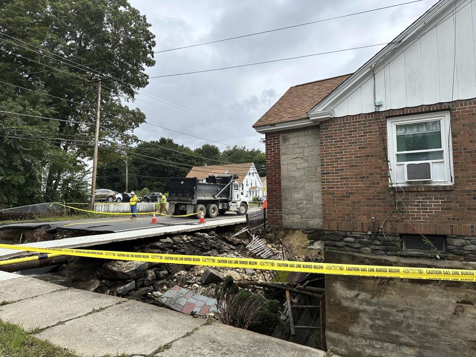 Yellow caution tape surrounds a sinkhole in Leominster, Mass., Tuesday, Sept. 12, 2023. Parts of Massachusetts and Rhode Island were flooded by heavy rain Monday night. (AP Photo/Michael Casey)