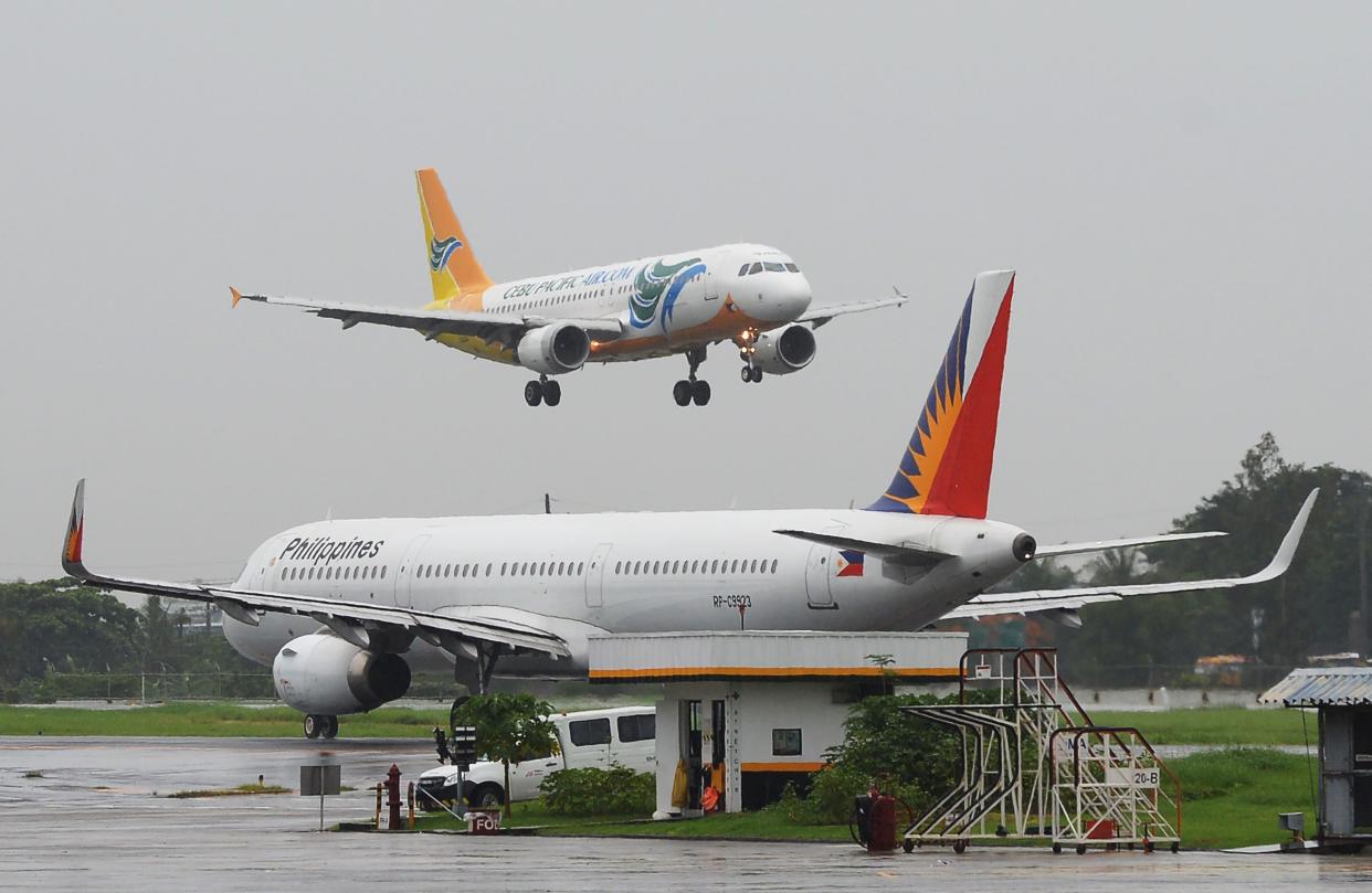 File Photo: A Cebu Pacific plane (top) preparing to land past a Philippine Airlines (PAL) plane (R) at Manila International Airport. (Photo: TED ALJIBE/AFP via Getty Images)