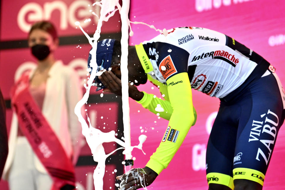 Eritrea's Biniam Girmay touches his eye after spraying sparkling wine on the podium to celebrate winning the 10th stage of the Giro D'Italia cycling race from Pescara to Jesi, Italy, Tuesday, May 17, 2022. Girmay was then taken to a local hospital after getting injured when he popped a champagne cork into his eye during the podium celebration. (Massimo Paolone/LaPresse via AP)