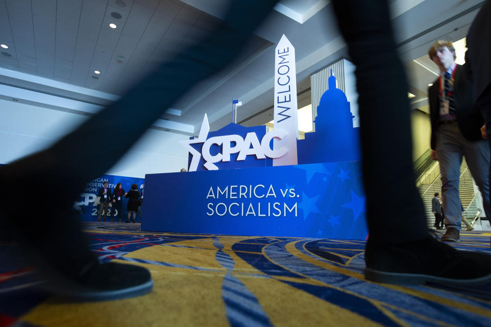 People pass by the CPAC sign, during Conservative Political Action Conference, CPAC 2020, at the National Harbor, in Oxon Hill, Md., Friday, Feb. 28, 2020. (AP Photo/Jose Luis Magana)