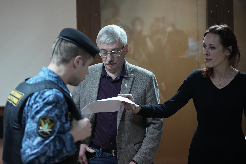 Oleg Orlov, a member of the Board of the International Historical Educational Charitable and Human Rights Society 'Memorial' (International Memorial), centre, looks on as his lawyer Yekaterina Tertukhina, right, holds a document after a court session in Moscow, Russia, Wednesday, Oct. 11, 2023. The court ordered Orlov, co-chair of the Nobel Peace Prize-winning human rights group Memorial, to pay a fine of nearly $1,500 on the charges of "discrediting" the Russian military in his criticism of Russia's campaign in Ukraine. (AP Photo/Alexander Zemlianichenko)