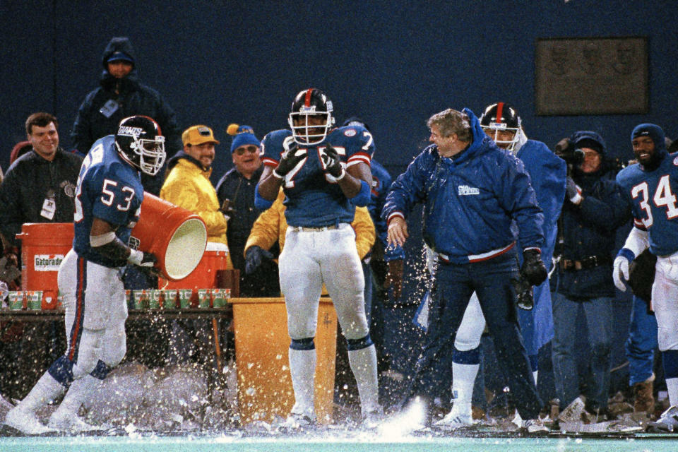 FILE - In this Jan. 11, 1987, file photo, New York Giants George Martin (75) watches as teammate Harry Carson empties the water bucket on coach Bill Parcells during the last minute of their 17-0 win over the Washington Redskins in the NFC championship in East Rutherford, N.J. Teams are never supposed to choose to kick off after winning the coin toss because it means they won't get the ball to start either half. But games rarely have wind gusts of 25 mph and beyond. That was the case when the Giants beat the Redskins 17-0 for the 1986 NFC title. (AP Photo/Elise Amendola, File)