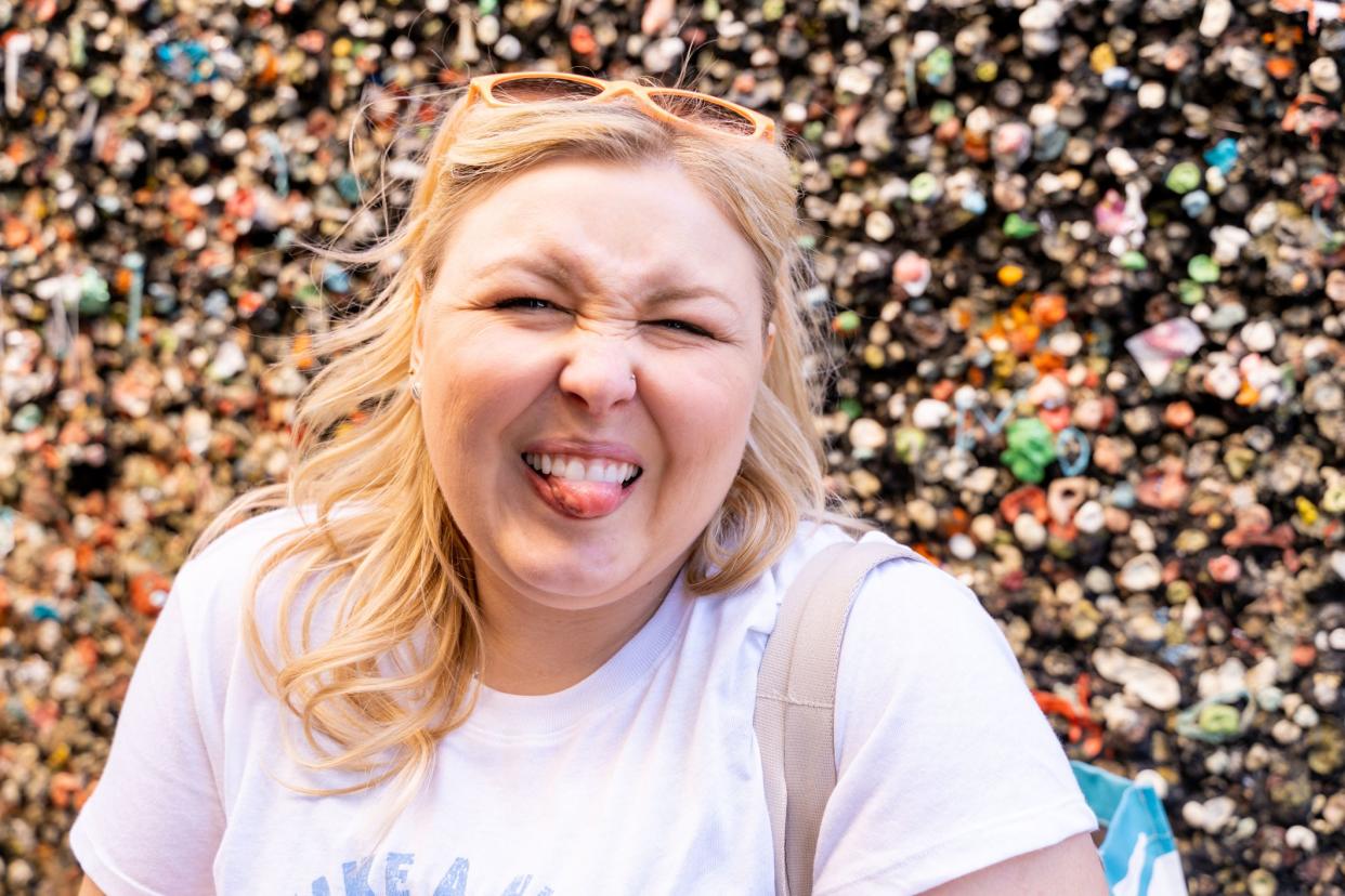Blonde woman makes a gross face with her tongue out while visiting the Bubblegum Alley wall in San Luis Obispo California