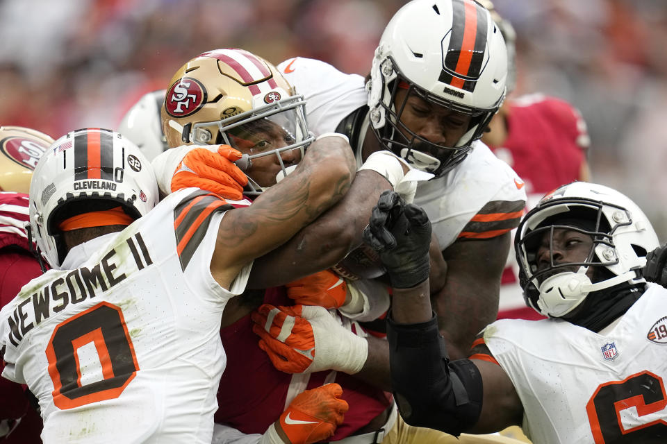 San Francisco 49ers running back Jordan Mason, middle, is tackled by Cleveland Browns cornerback Greg Newsome II (0), linebacker Jeremiah Owusu-Koramoah, bottom right, and defensive end Za'Darius Smith during the second half of an NFL football game Sunday, Oct. 15, 2023, in Cleveland. (AP Photo/Sue Ogrocki)