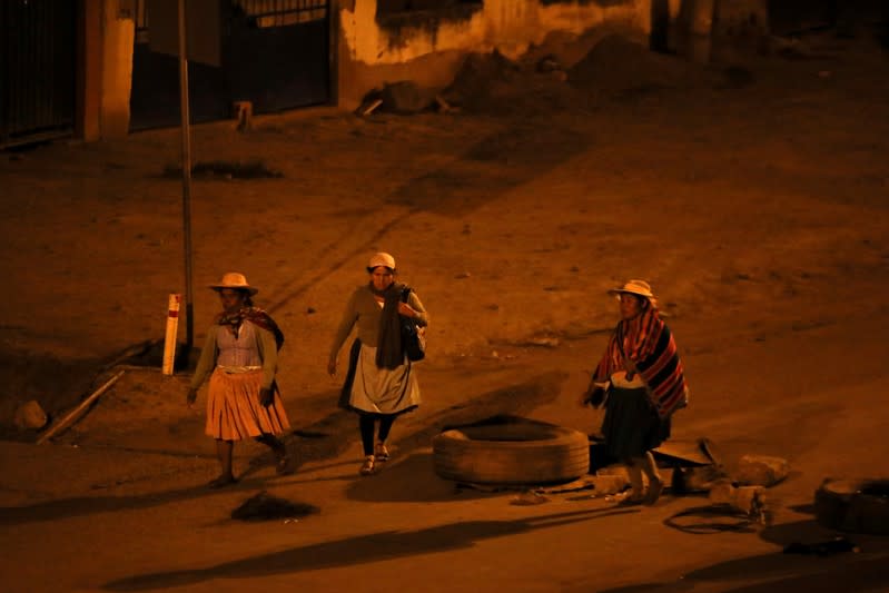 Women walk through a barricade as coca farmers and supporters of Bolivia's ousted President Evo Morales stage a blockade of an entrance to Sacaba