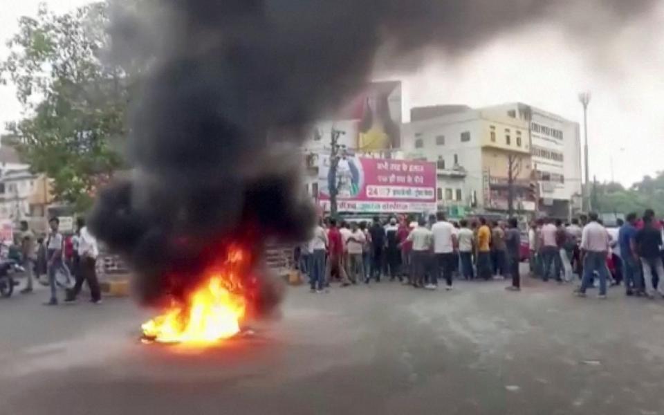 Smoke rises from burning material on the road as tensions rise in Udaipur - /ANI via REUTERS 