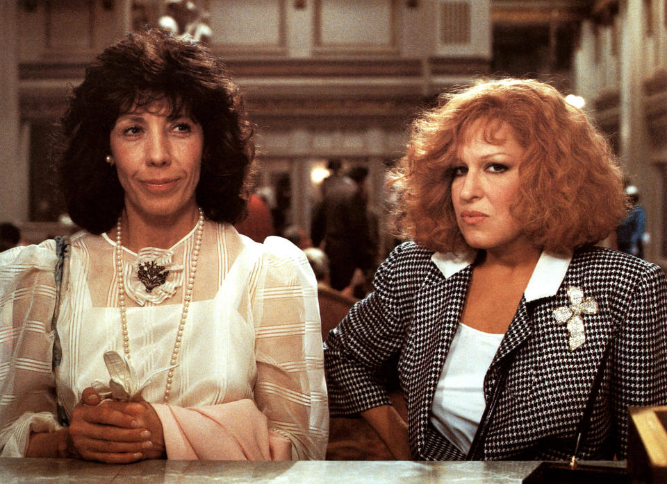 Lily Tomlin and Bette Midler stand at a counter