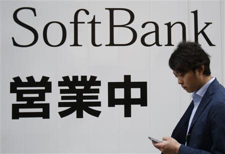 A man holding his mobile phone walks past the logo of Softbank Corp at its branch in Tokyo April 22, 2014. REUTERS/Yuya Shino