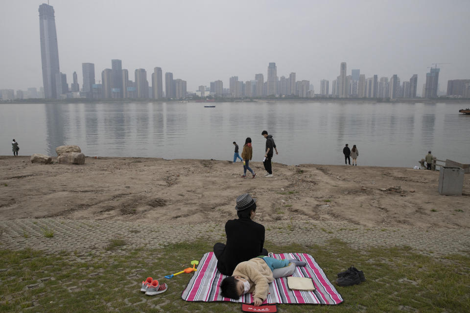 A child wearing a face mask takes a nap along the Yangtze River in Wuhan in central China's Hubei province on April 5, 2020. (AP Photo/Ng Han Guan)