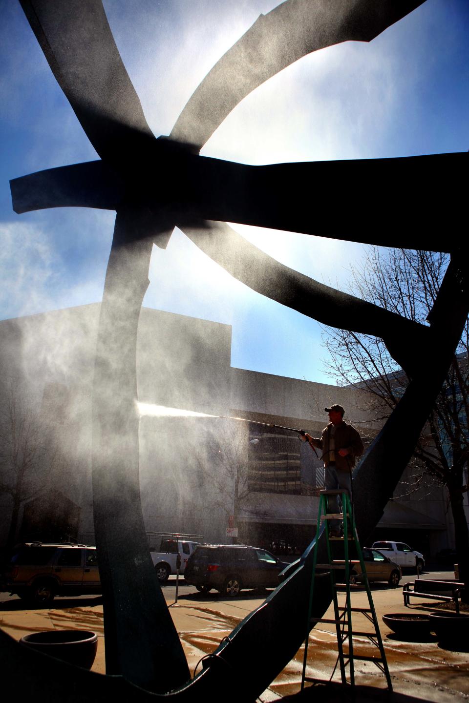 Gary Howe of Indianola creates a heavy mist while trying to spray wash bird droppings on Tuesday, April 12, 2011 from Crusoe Umbrella at Nollen Plaza next to the Civic Center of Greater Des Moines. He said the power washer might not be enough and he would get a portable lift so he could wipe them off.